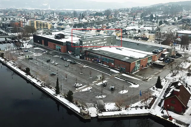 Luftfoto av bygning i bymiljø om vinteren, med Volvat-plassering markert i rødt.