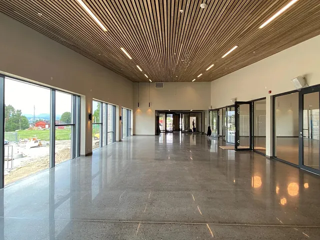 Langstrakt inngangsparti med store glassflater og åpen utsikt mot grønt landskap.