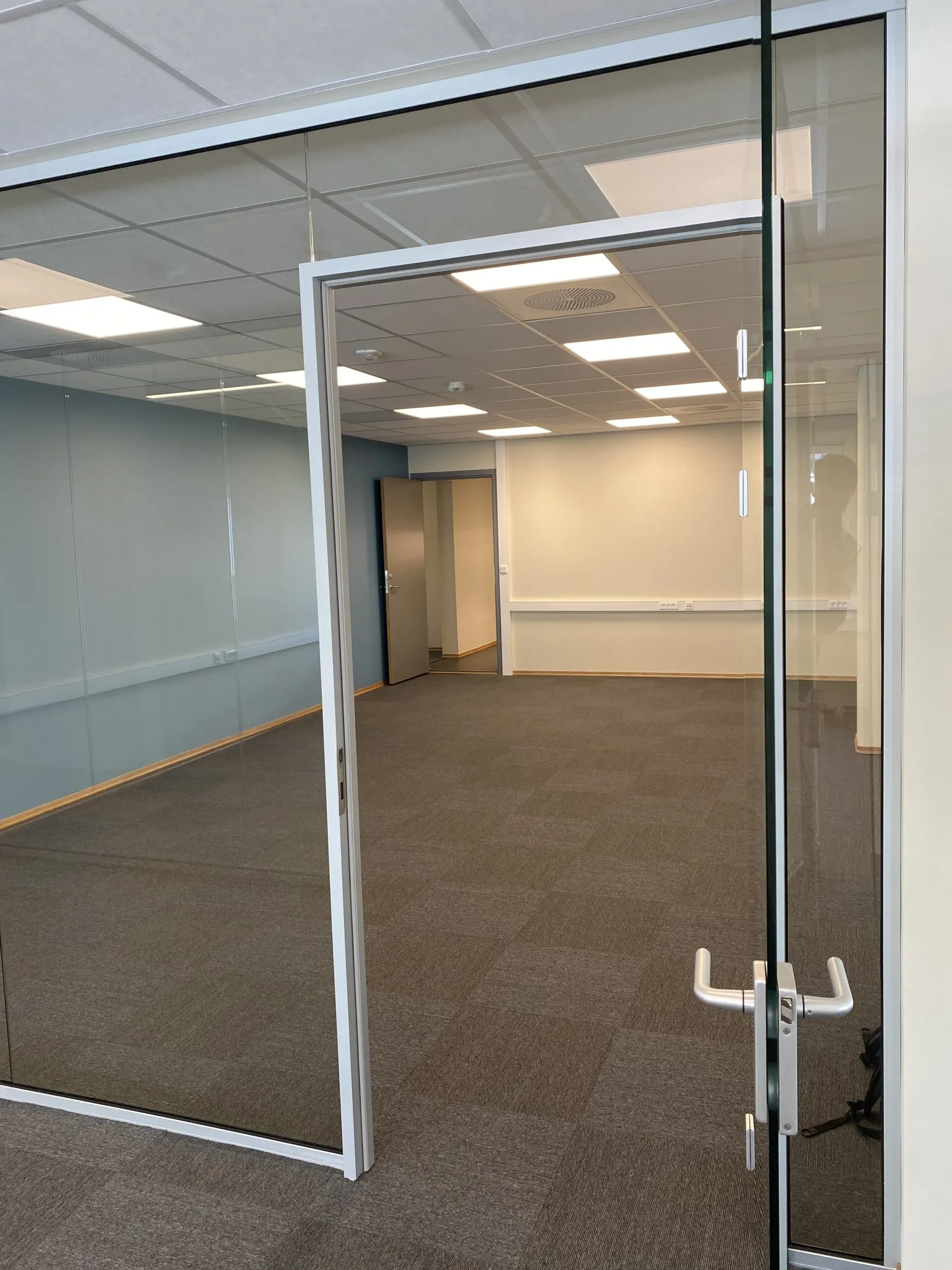 utsikt til større tomt rom fra kontor med glassdør