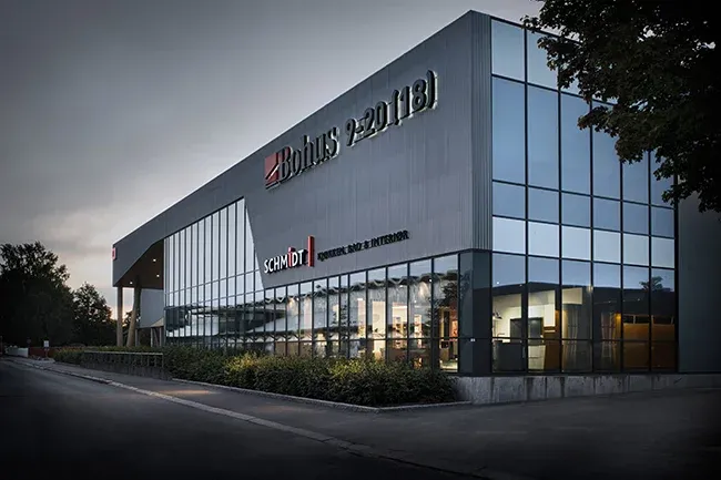 Fasade av møbelbutikk med skilt for Bohus og Schmidt, store vinduer og mørk kledning.