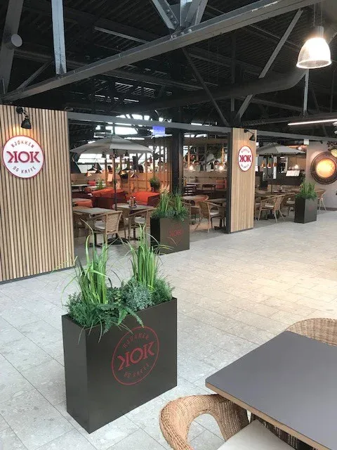 Restaurantområdet KOK med sitteplasser, grønne planter og lun belysning i kjøpesenter.