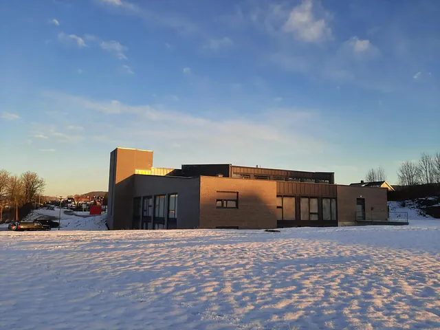 Sidevisning av kirken i vintersol, med store vinduer og lav sol bak bygget.