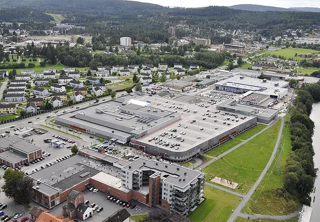 Luftfoto av Herkules kjøpesenter omgitt av boliger, med stort tak og mange parkeringsplasser.