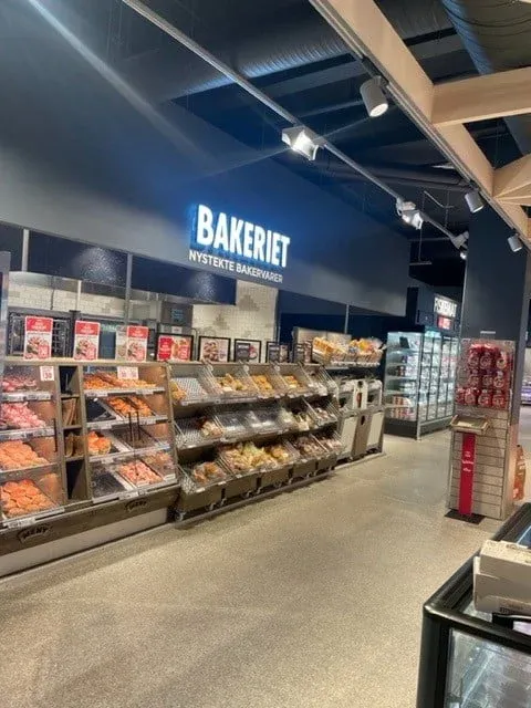 Bakeriavdeling i dagligvarebutikk med godt utvalg av nystekte bakevarer i åpne hyller.