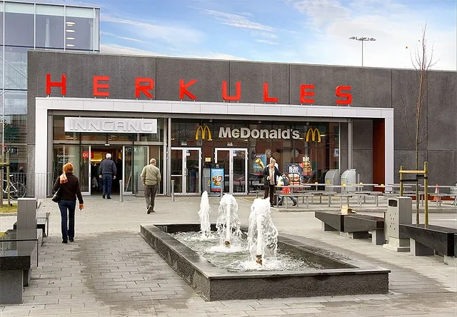 Inngangsparti til Herkules kjøpesenter med fontene foran og McDonald’s rett innenfor dørene.